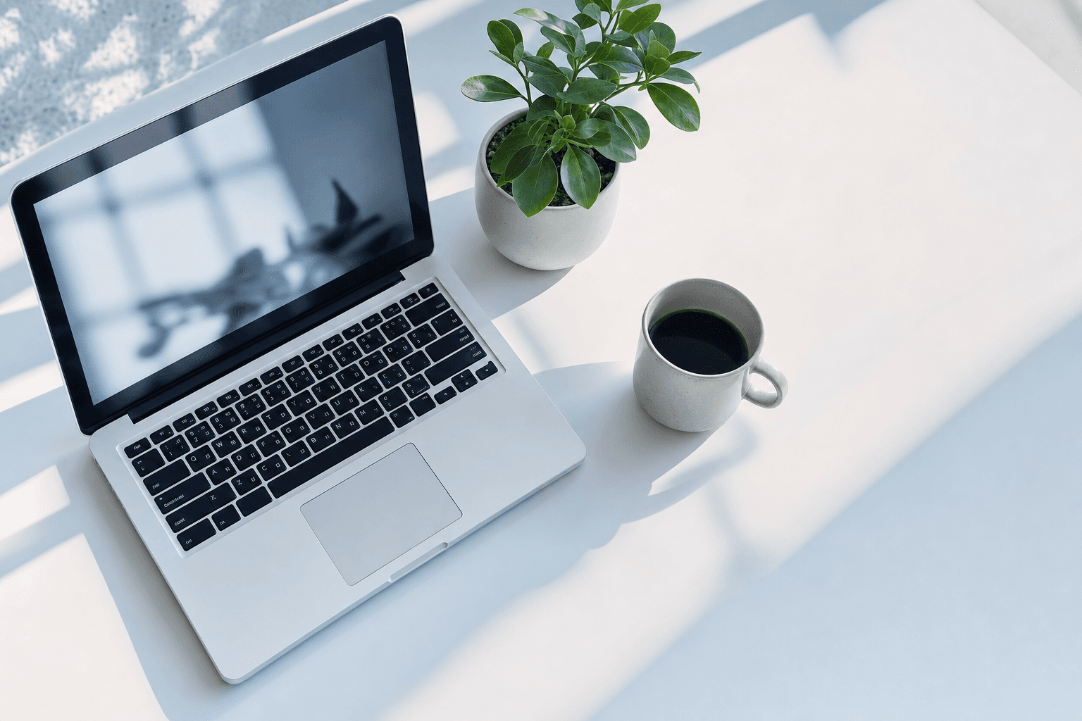 Minimal home office desk with a laptop, coffee mug, and plant